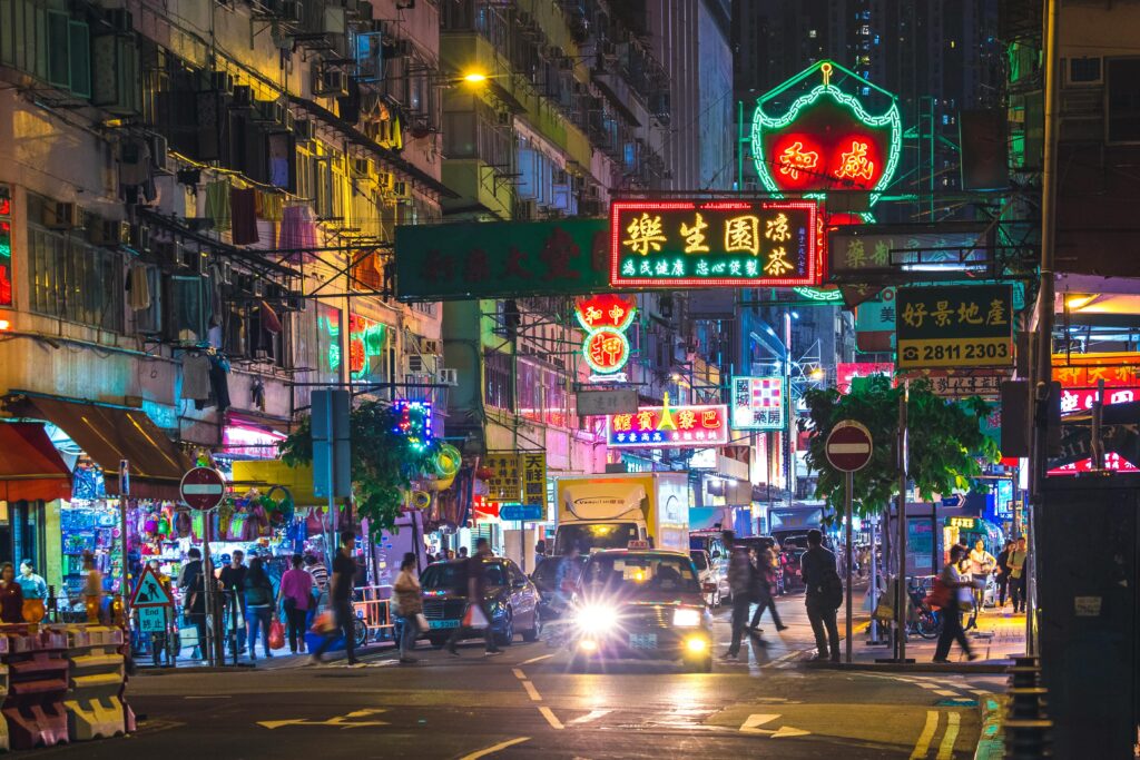 Colorful neon lights illuminate a bustling street in the New Territories, Hong Kong, by night.