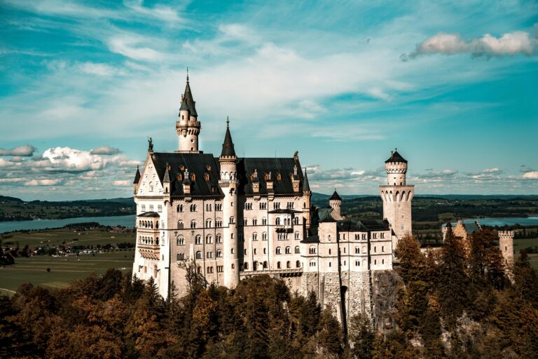 Stunning aerial view of Neuschwanstein Castle in Bavaria, Germany, against a bright blue sky.